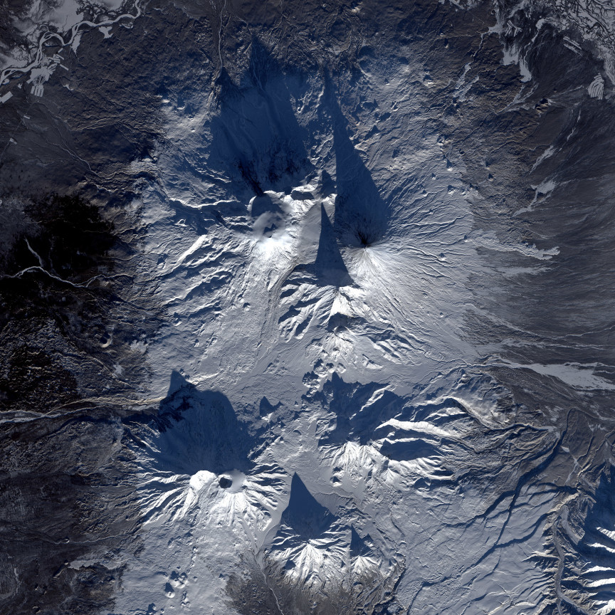 En este detalle de la imagen podemos ver hasta siete volcanes proyectando su alargada sombra sobre la nieve y la gélida superficie de la península de Kamchatka. Landsat/NASA/USGS.